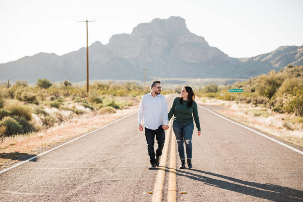 Salt river Arizona Engagement session couple walking in road in front of red mountain 
