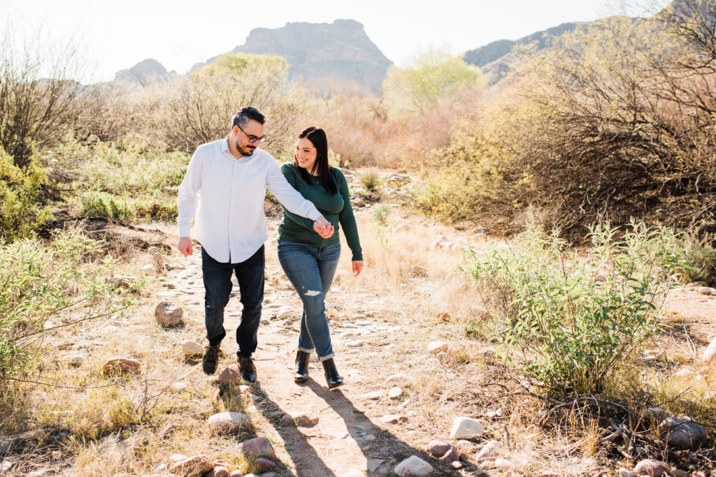 couple laughing and walking in the desert red mountain in the back