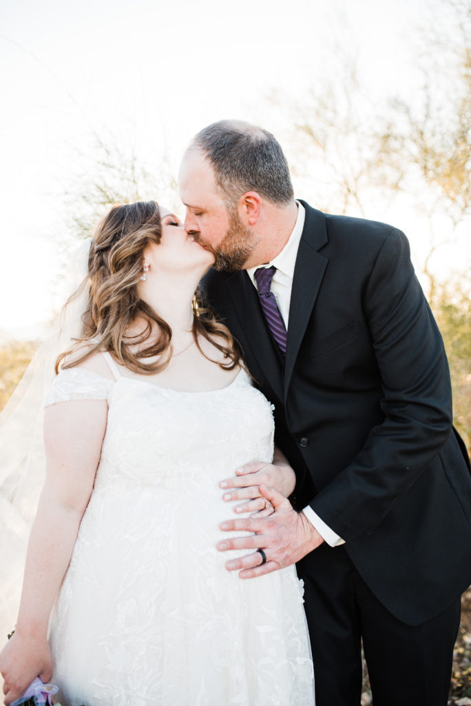 wedding couples portraits kissing with hand on belly pregnant bride 