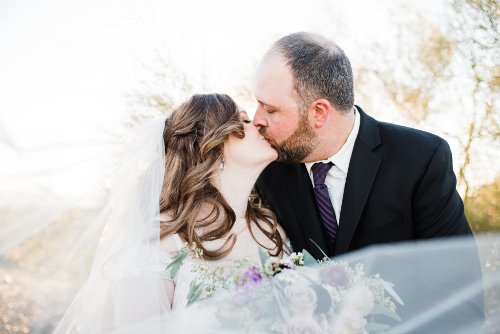 wedding couple kissing close up with bouquet and veil