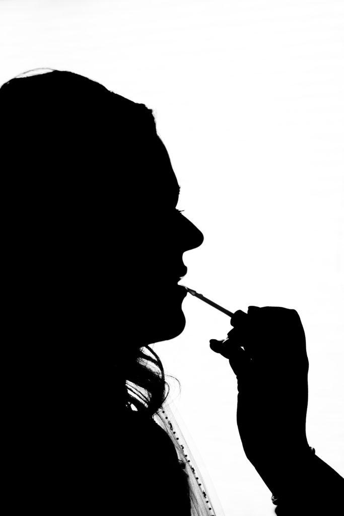 silhouette of bride getting lipstick on
 