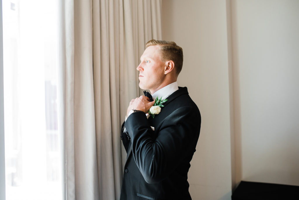 Groom before ceremony looking out window 