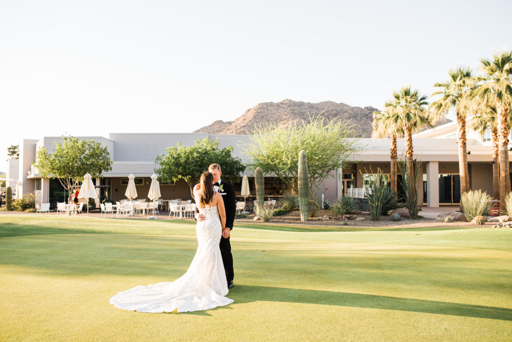 Bride and groom walking at mountain shadow resort on golf course with mountains in the back