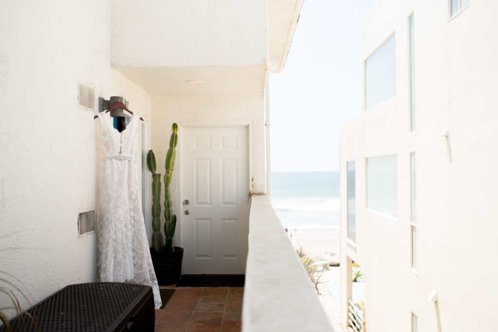 wedding dress hanging in front of door with beach in the back ground 