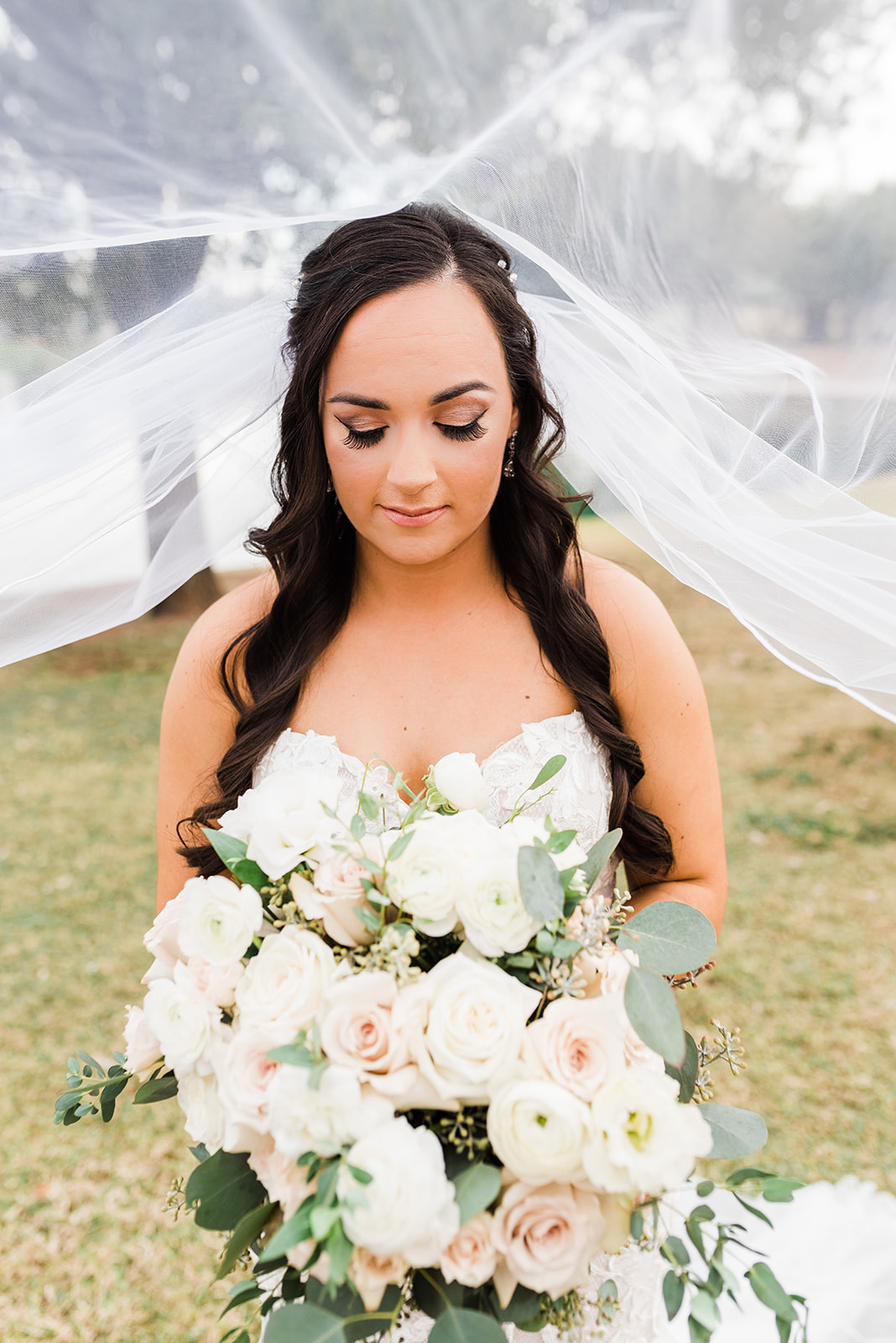 bride under her veil looking at her bouquet at her ADERO Scottsdale Wedding