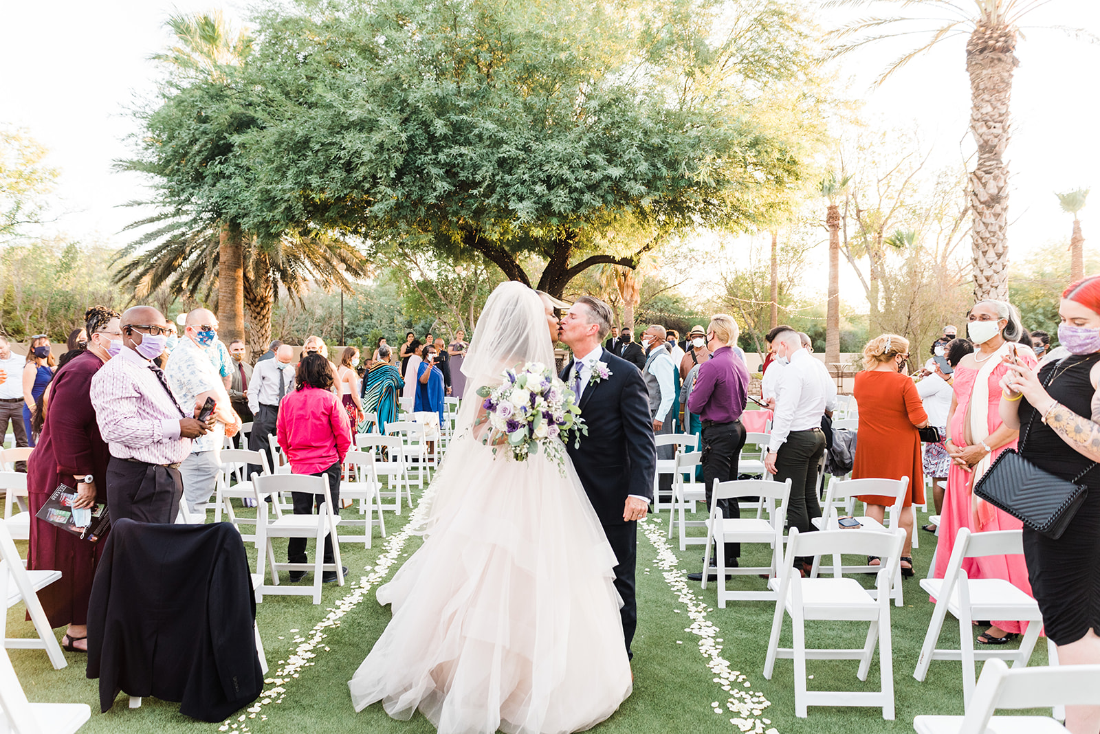 bride and groom sharing a kiss as they walk down the aisle at the Secret Garden Phoenix wedding venue