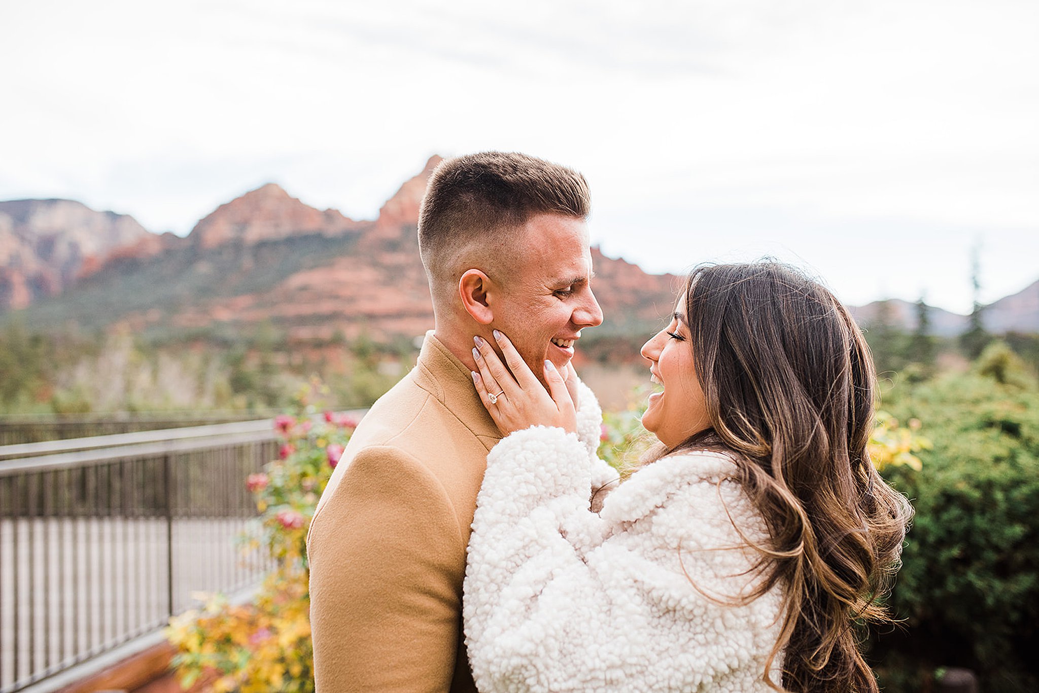 woman holding her fiance's face with red rocks behind him