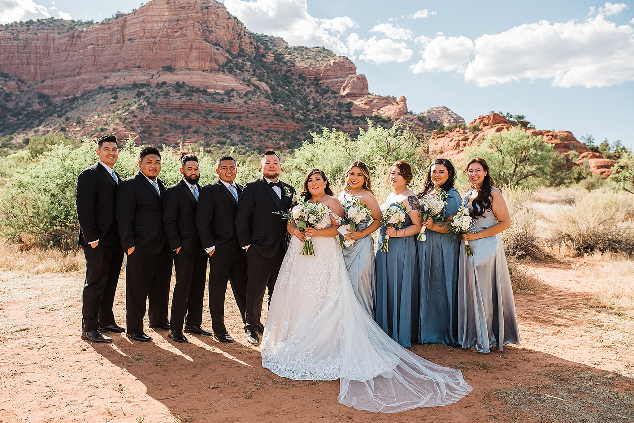 wedding party standing in front of the red rocks