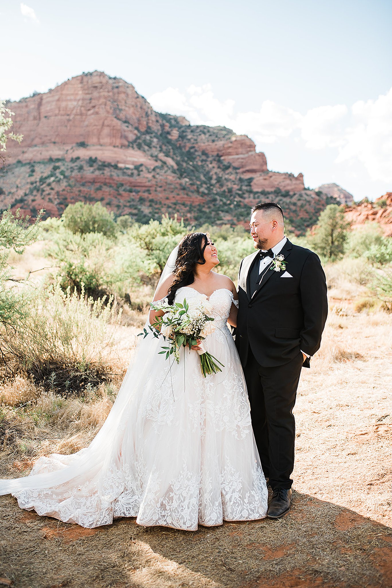bride and groom looking at each other in front of the red rocks