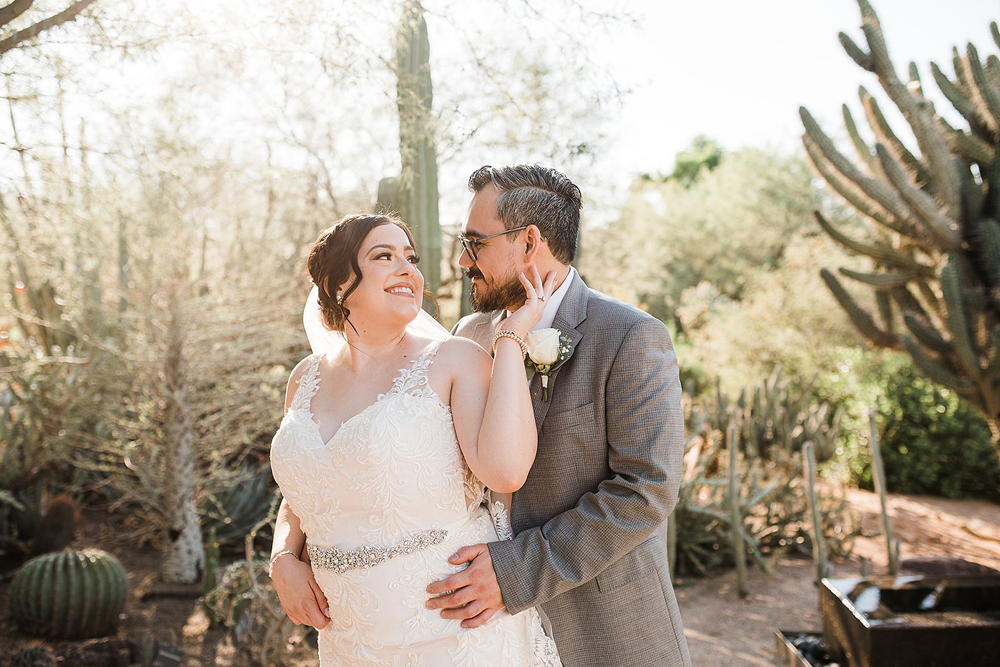 bride holding her groom's face as he hugs her from behind at their desert botanical gardens wedding