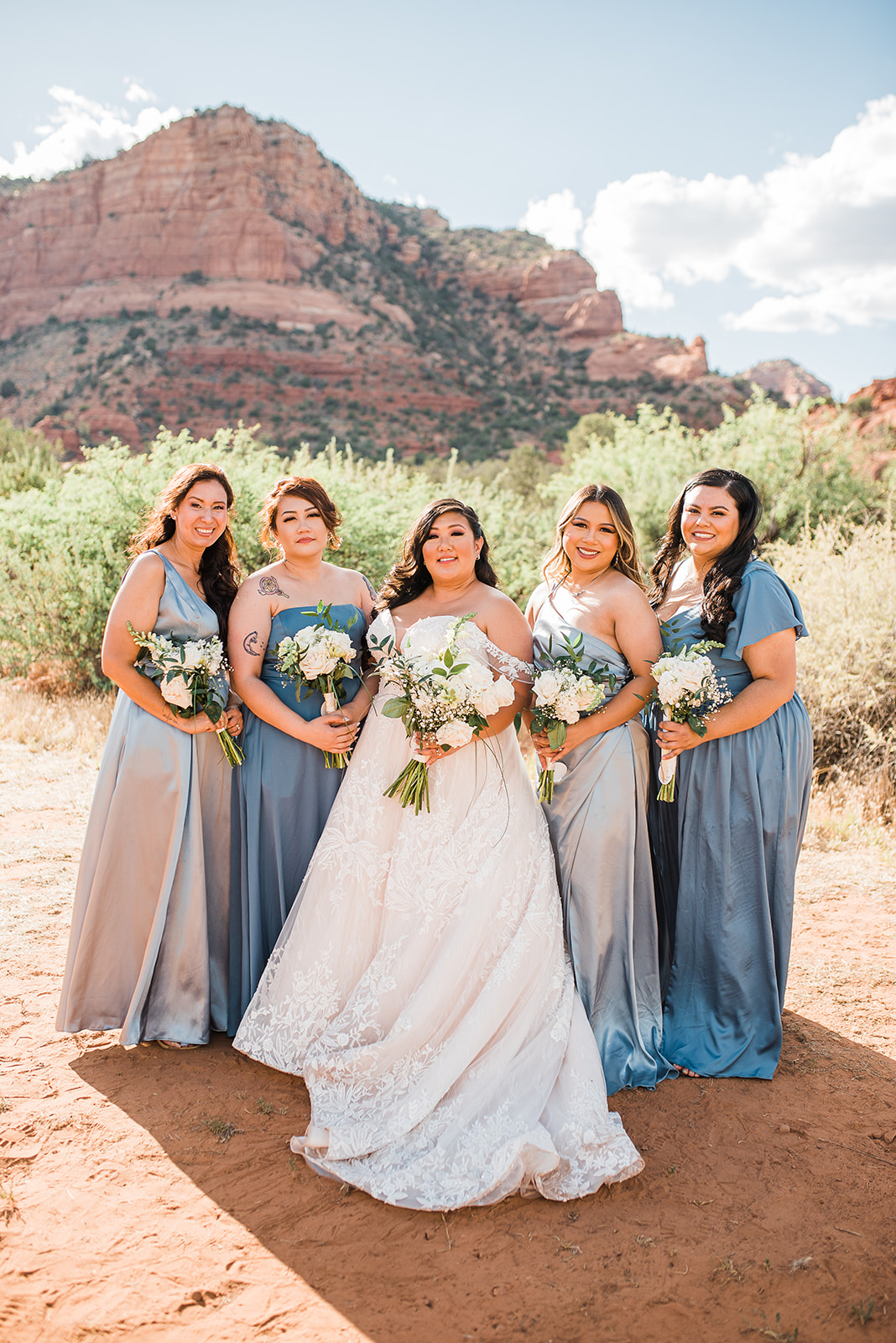 bridal party stands in the desert holding white bouquets