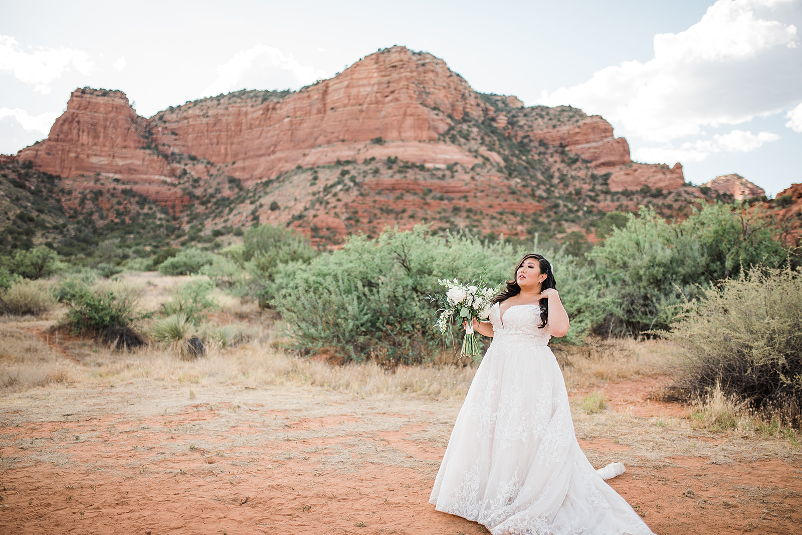 bride stands in the desert in front of large red rock mountain destination at oak creek wedding