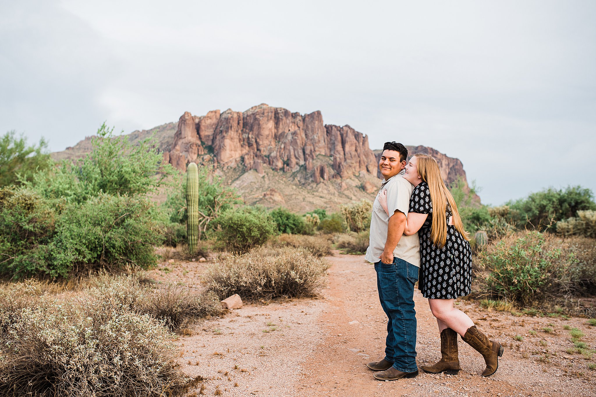 woman hugs her partner from behind in a desert path