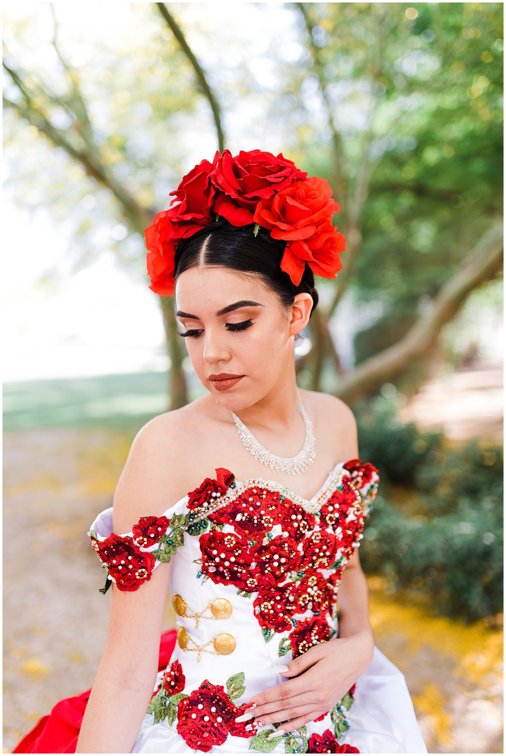 Teenager looks down her shoulder in an ornate red rose ballgown