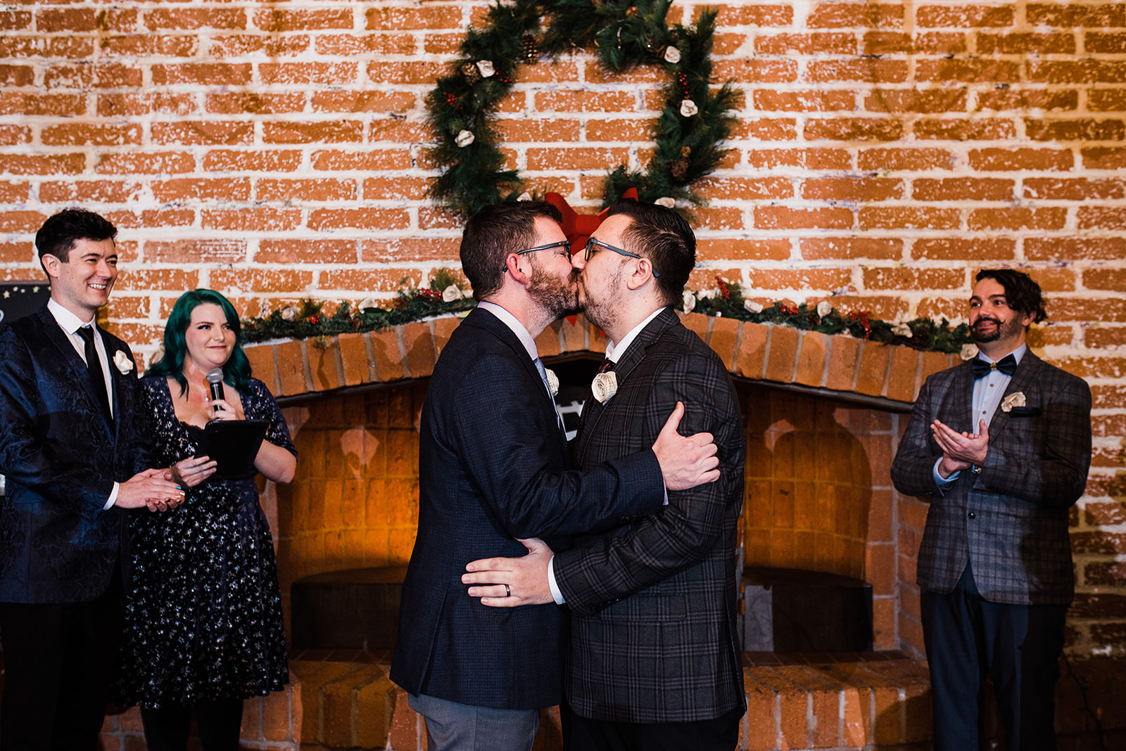 Newlyweds kiss under a Christmas wreath in front of a fireplace at The Newton Phoenix