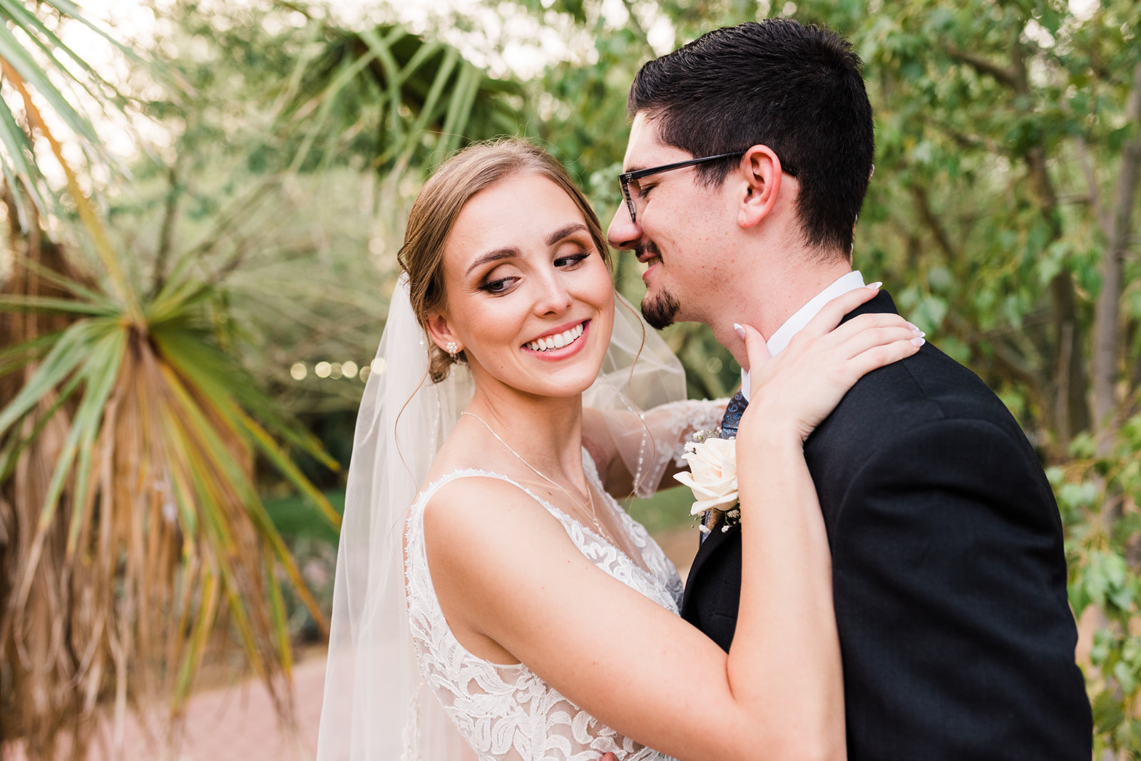 Newlyweds dance in a desert garden while wearing a white lace wedding dress and long veil at Antigua Garden