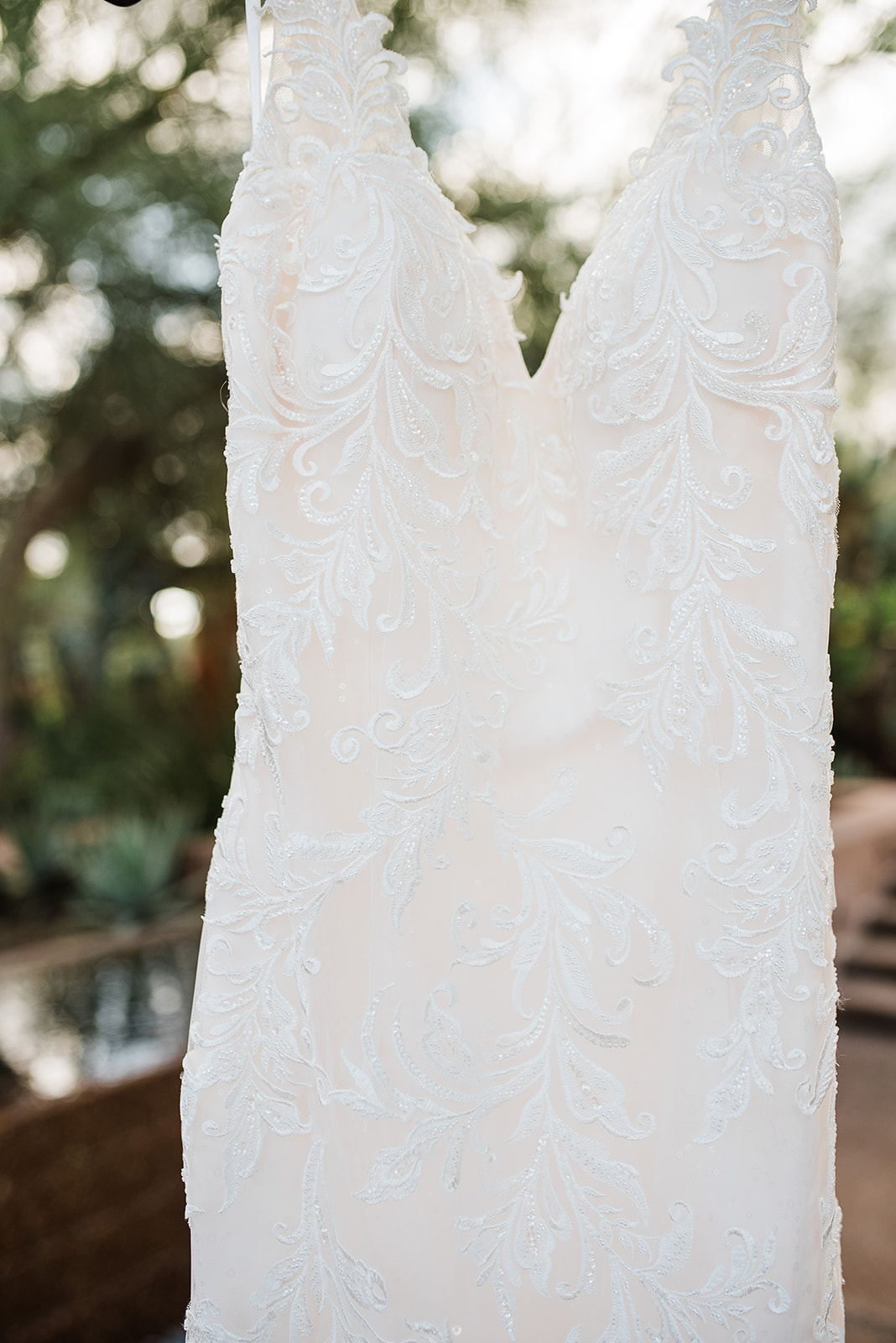 A white lace wedding dress hangs in a garden at Bella Rose Estate Wedding