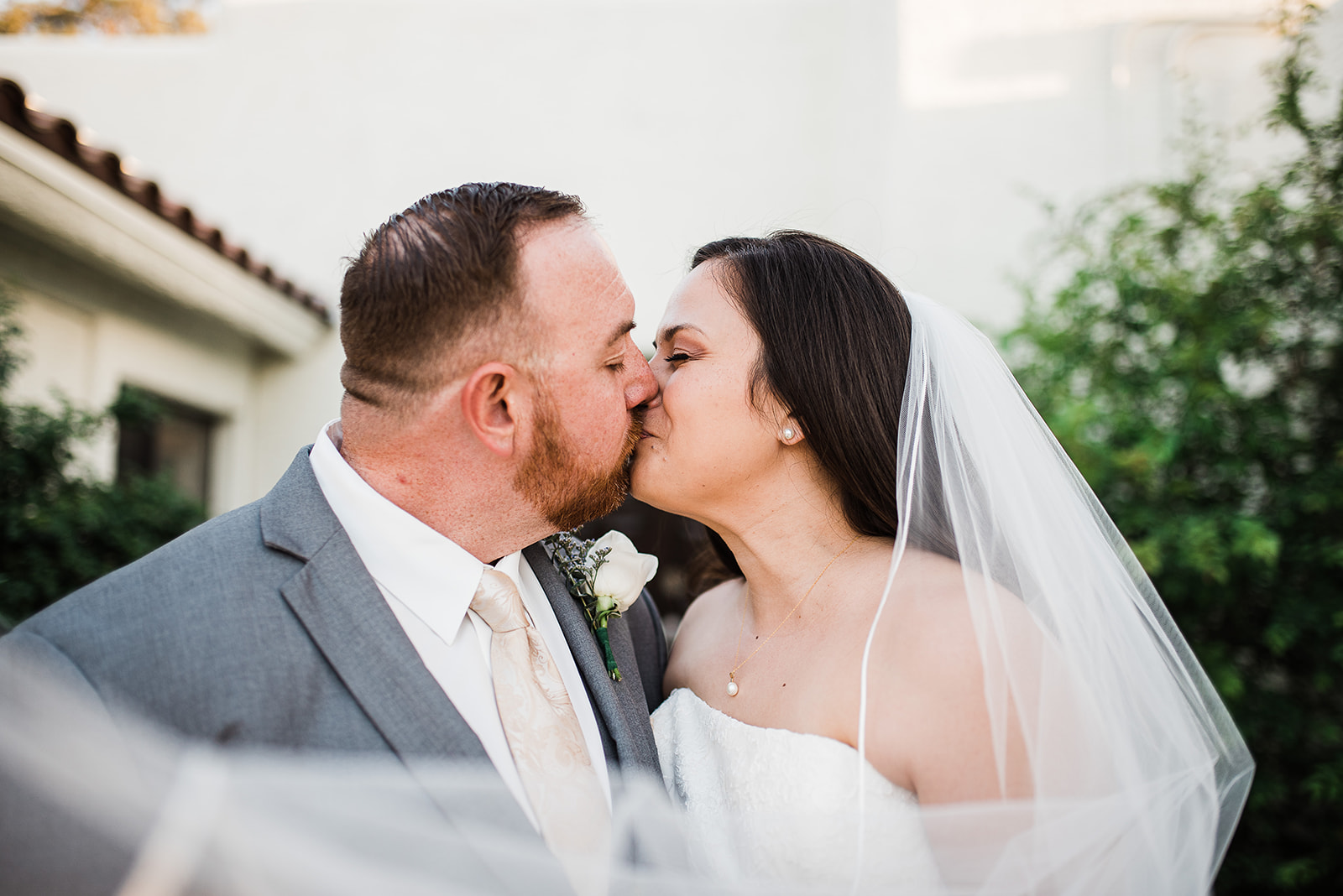 Newlyweds kiss in a garden with the veil flowing around them