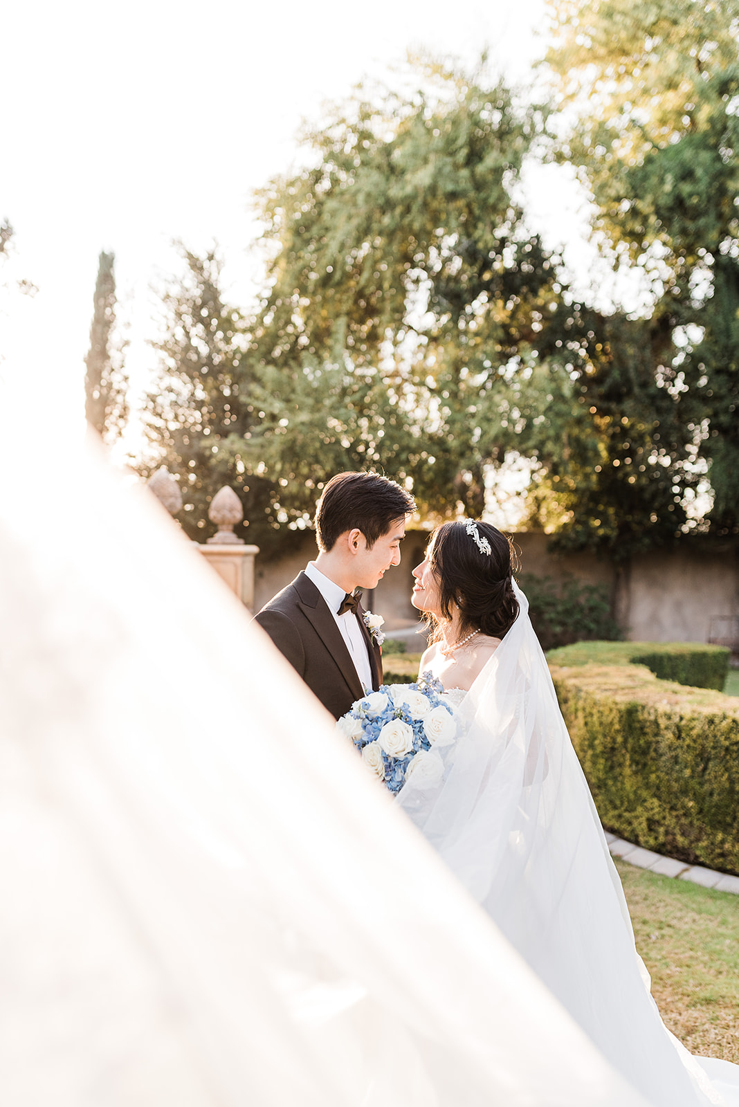 Newlyweds stand close leaning in for a kiss in a manicured garden at sunset in a Phoenix Country Club Weddings