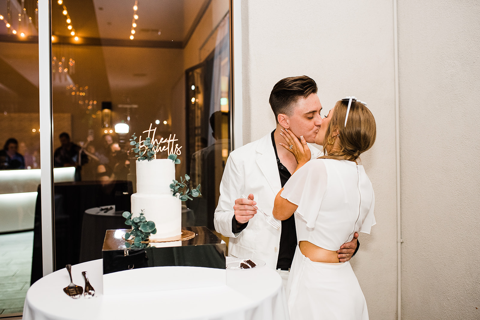 Newlyweds kiss in a white suit and dress after cutting their two tier cake planned by Phoenix Wedding Planners