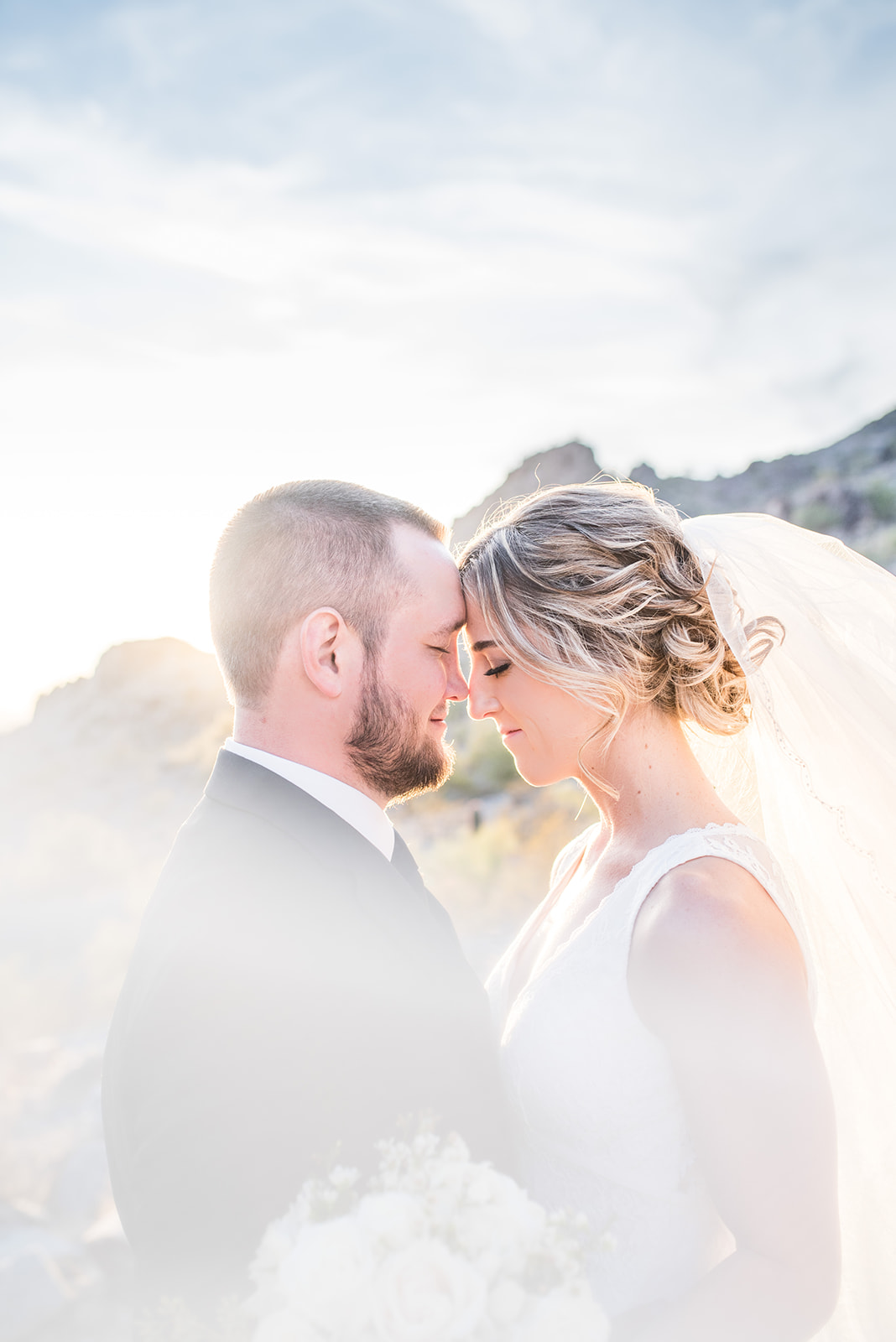 Newlyweds rest their foreheads together while standing in a desert trail at sunset during their Country Club At DC Ranch