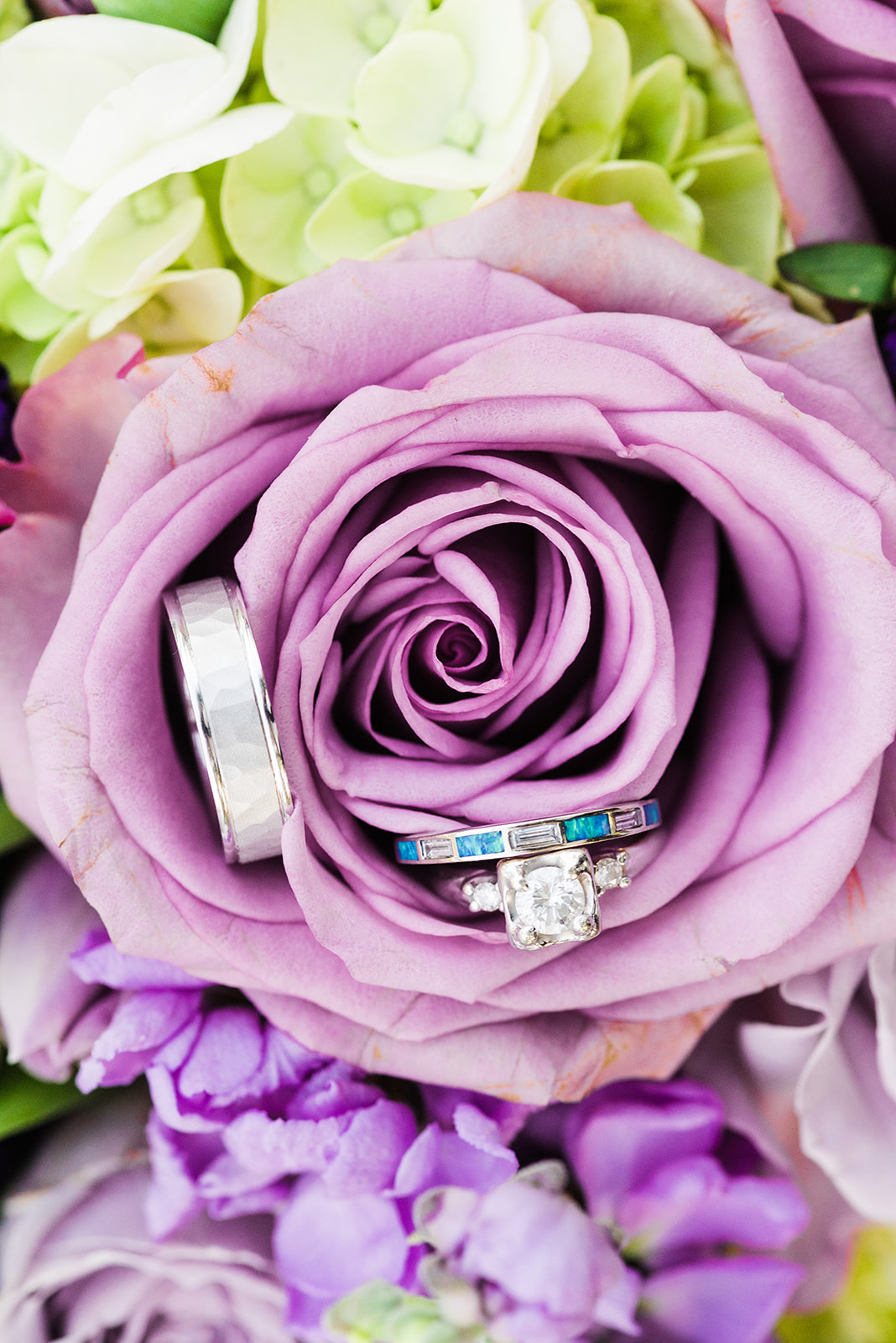 Details of wedding rings sitting in a purple flower