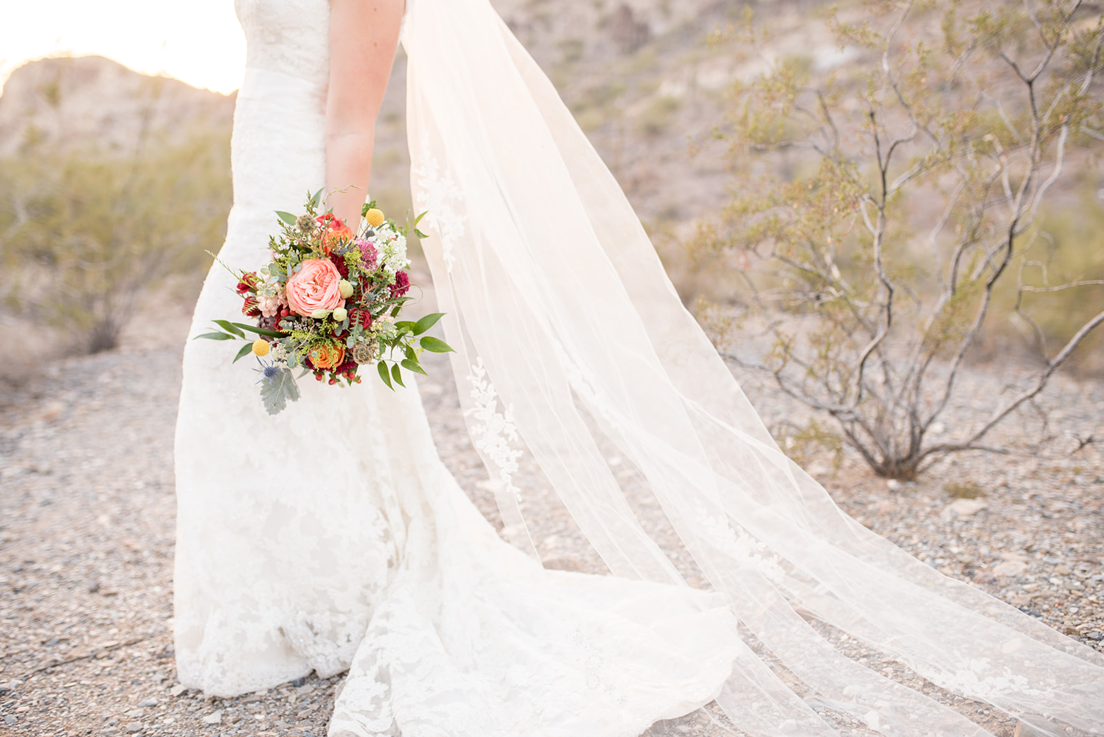 Details of a brides train flowing as she holds her colorful bouquet before a Four Seasons Scottsdale Wedding