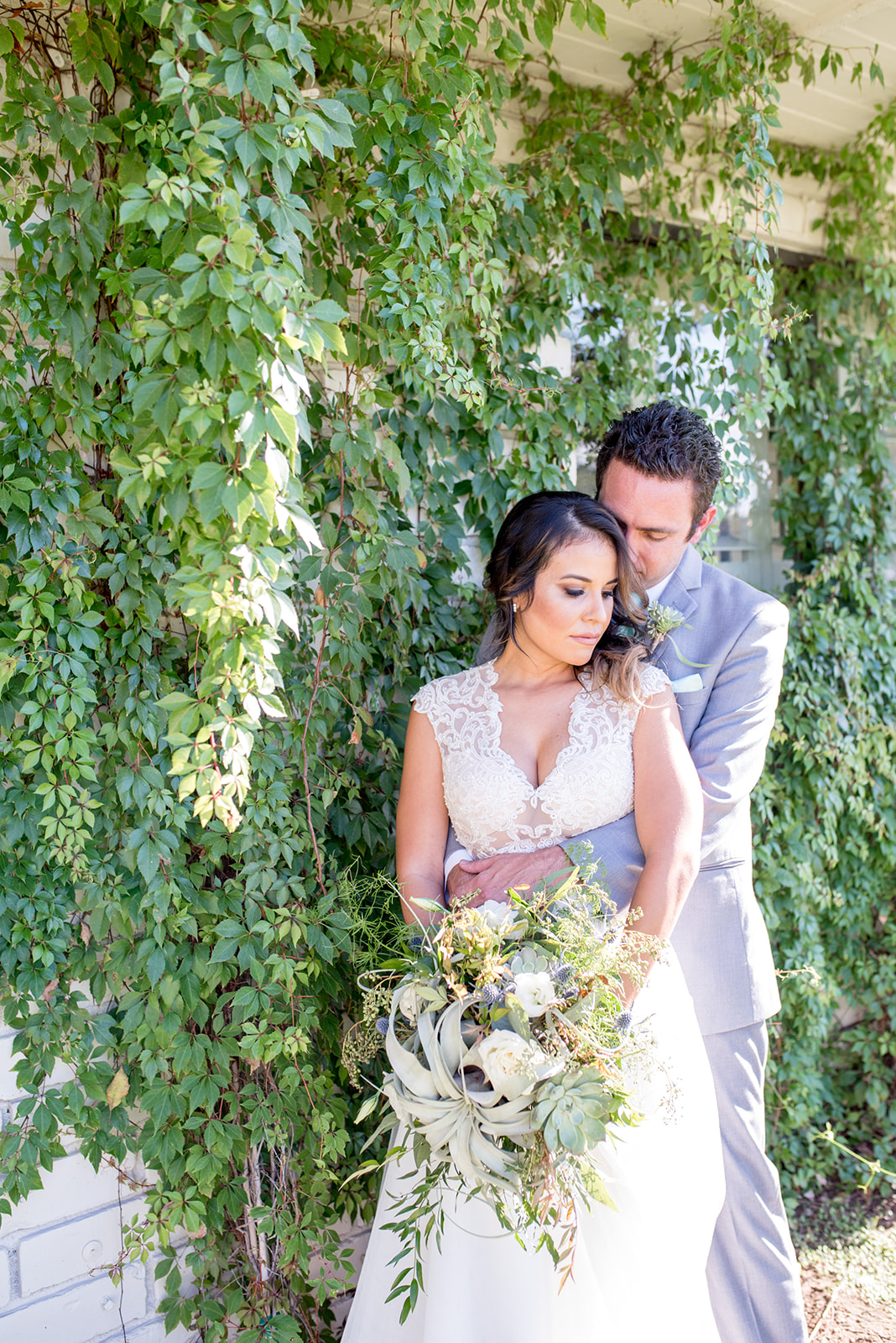 Newlyweds share an intimate moment on a wall of vines