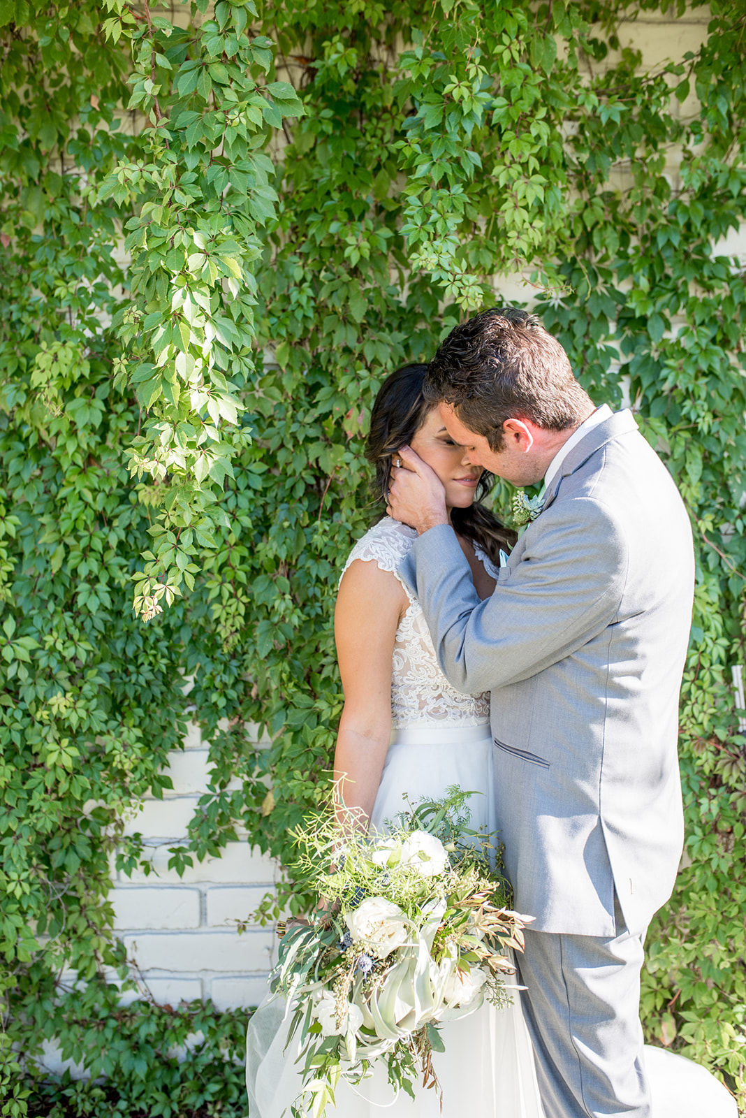 Newlyweds lean in for a kiss in front of a wall of vines at a Villa Siena Wedding